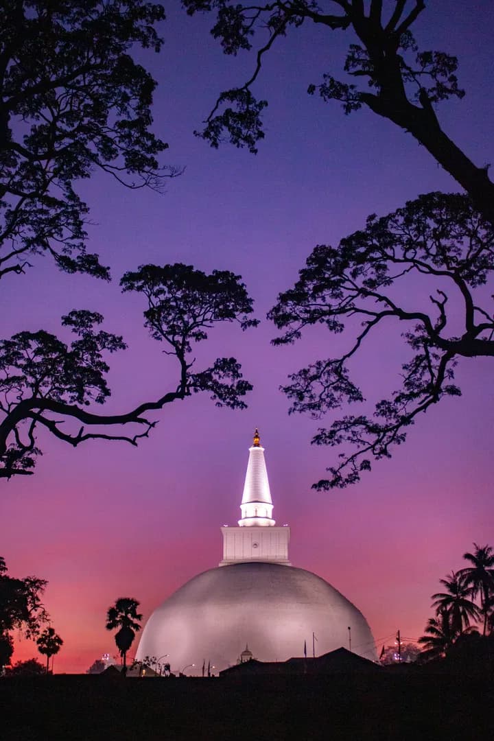White dagoba temple against purple sunset sky